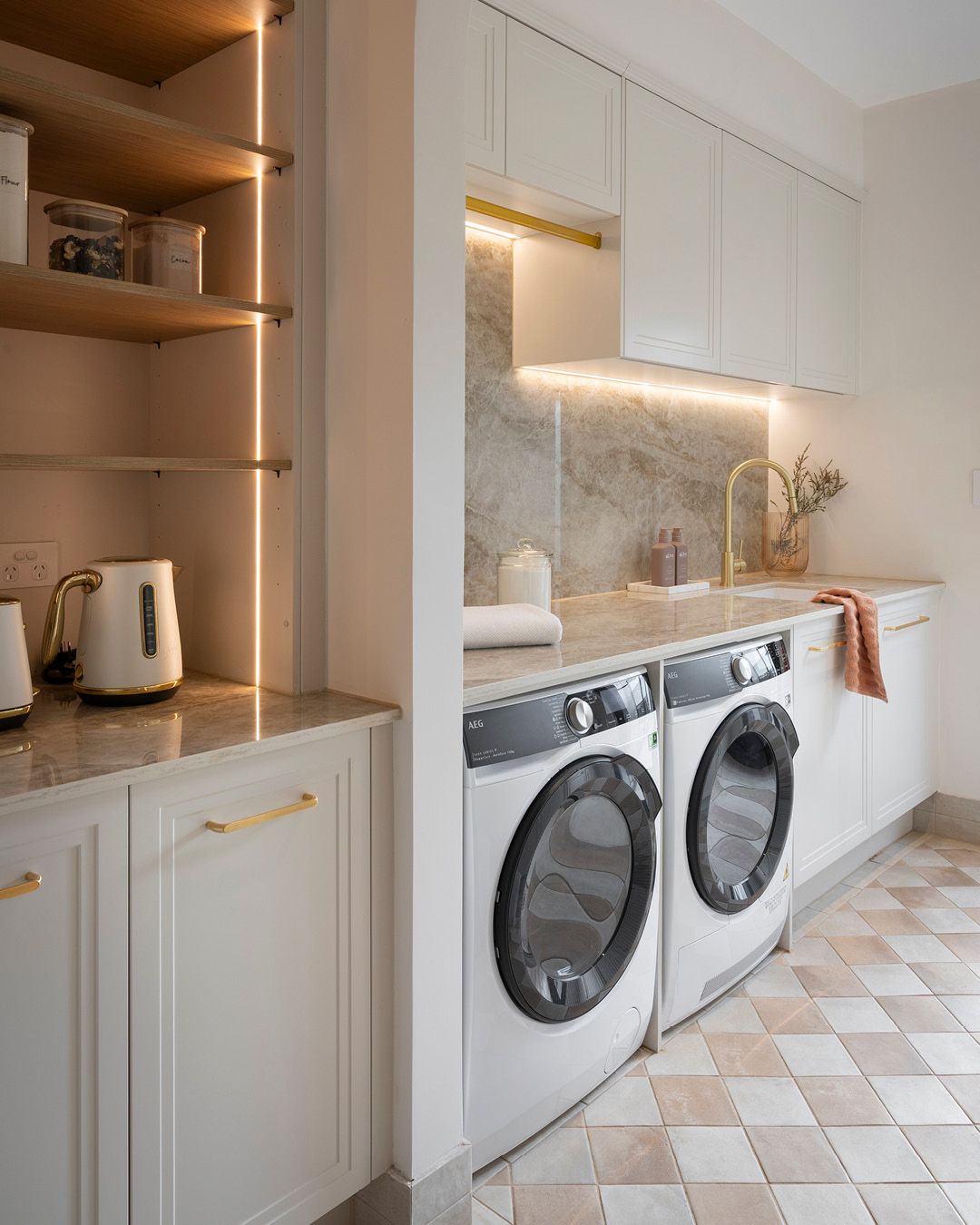 Laundry room with washing machine, clothes dryer, hanging rail and white Shaker-style cabinets.