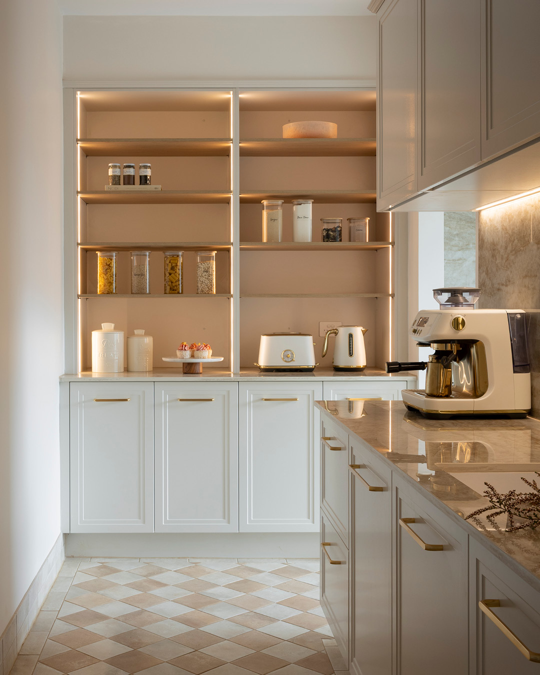 Pantry storage with oak shelving, shaker-style cupboards and gold handles.
