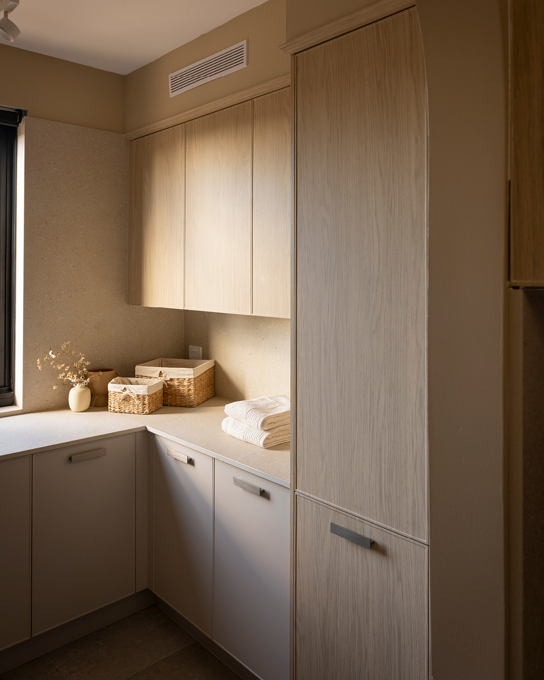Neutral coloured laundry room with tall cupboards