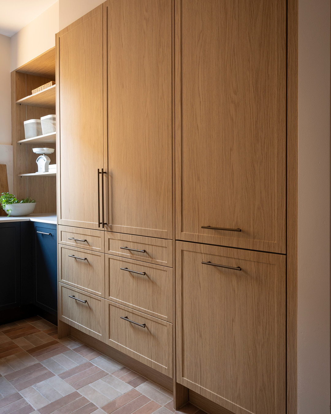 Pantry storage tall cupboard in Oak Shaker-style cabinetry with bronze bar handles.