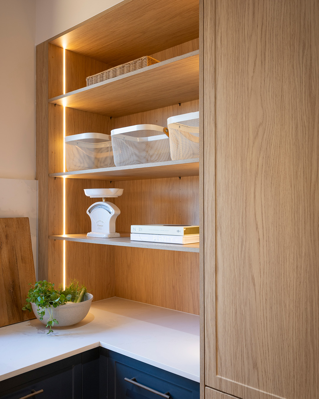 Pantry with open shelving in timber-look joinery and vertical strip lighting,
