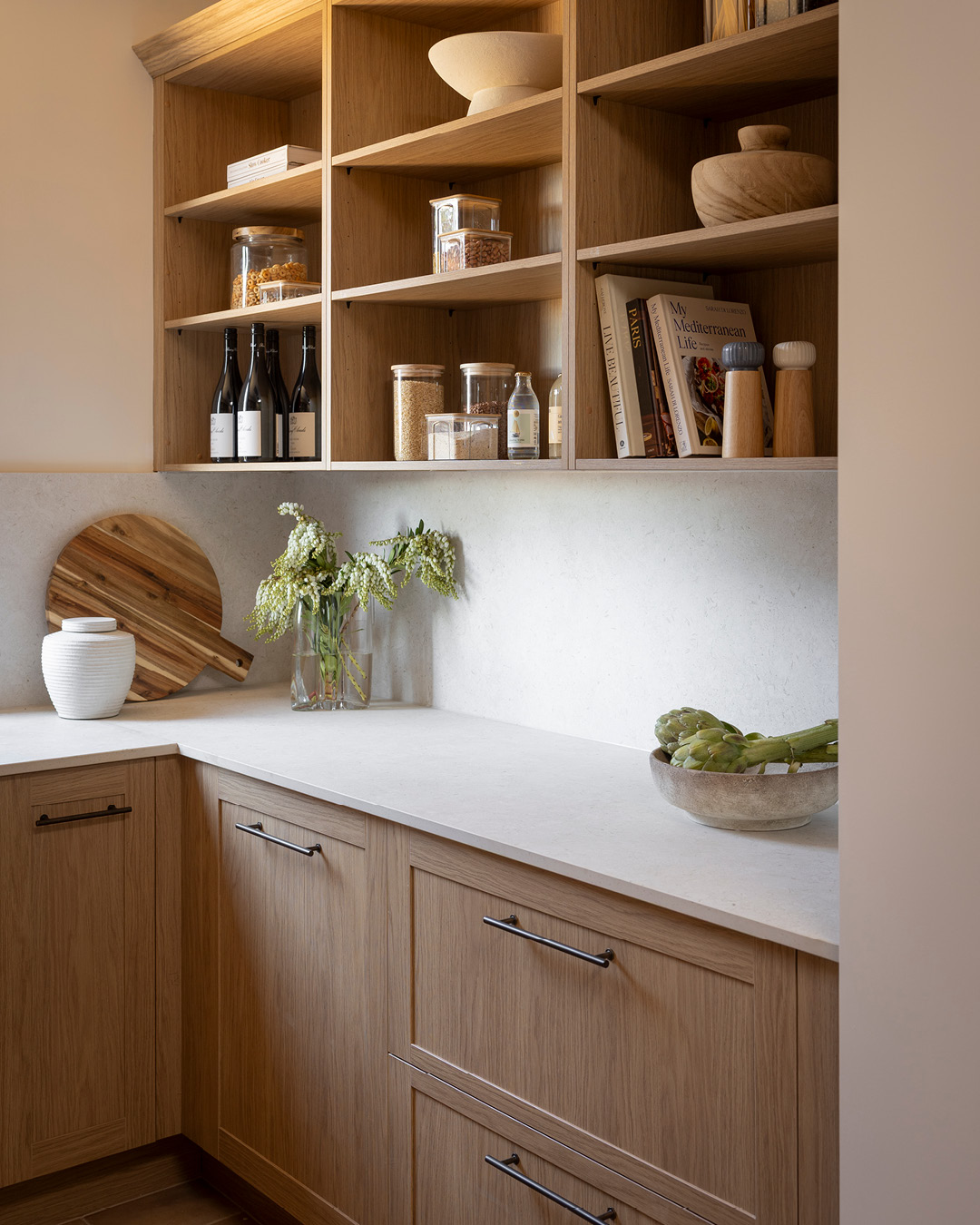 Kitchen pantry with timber-look open shelves, floor cupboards and a white benchtop.