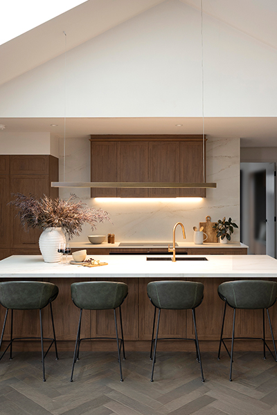 Kitchen illuminated by warm LED strip lighting along shelving and a striking pendant light above the island.