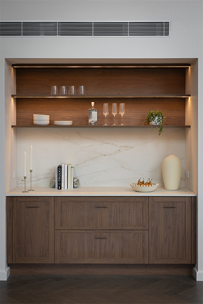 Warm, earthy kitchen palette with toasted chestnut cabinetry, marble-effect island, and copper bronze handles.