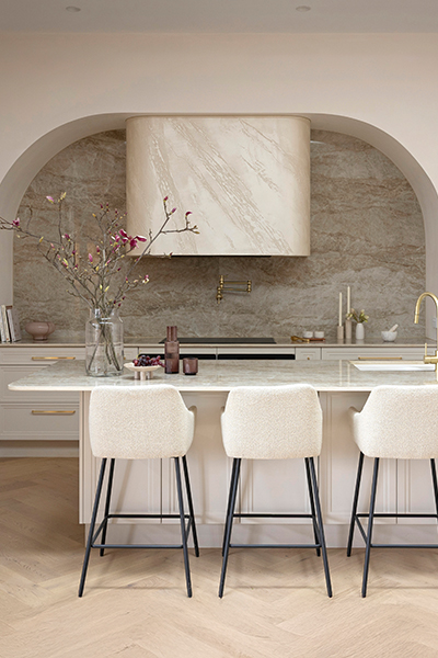 Statement kitchen with flowing curved design, combining sleek cabinetry, marble-effect island benchtop, and luxe brushed gold hardware.