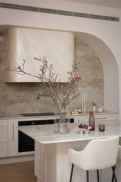 Amaro Smooth cabinetry with Nordic Oak pantry interiors, brushed gold bar handles, and curved Dekton Taga benchtop creating a luxurious, contemporary kitchen.