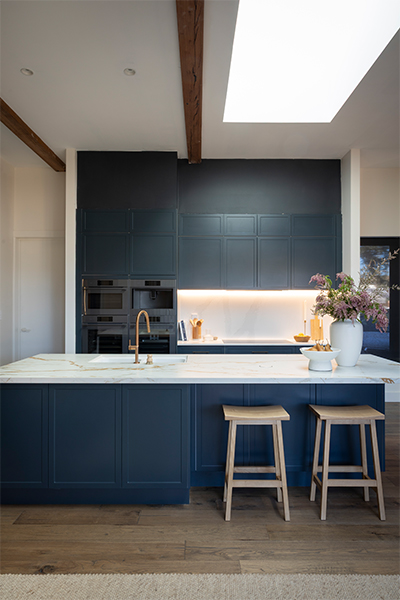 Statement kitchen combining Baltic Blue cabinetry, layered stone surfaces, and refined modern finishes for a warm, inviting space.