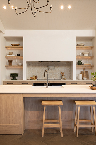 Modern farmhouse kitchen with warm timber cabinetry, white benchtops, and green accents.