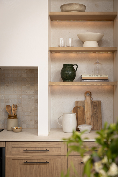 Farmhouse-style kitchen with floating oak shelves, styled with simple, elegant decor.